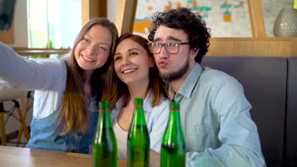 Três amigos se sentam em um café, se divertem se comunicando e fazem selfie. Movimento lento — Vídeo de Stock