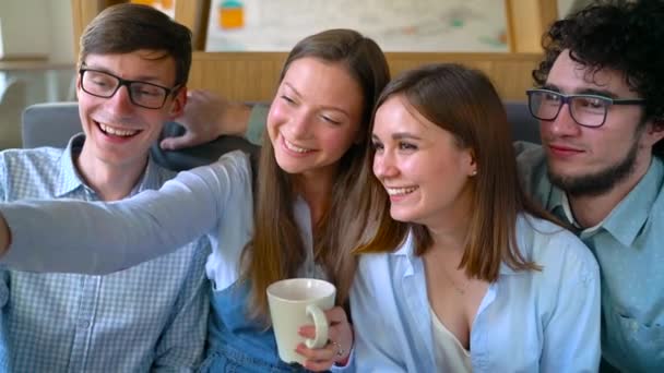 Amigos sonrientes se sientan en un café, se divierten comunicándose y hacen selfies. Movimiento lento — Vídeos de Stock