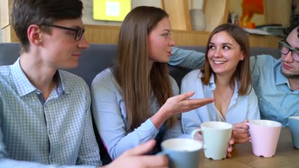 Jóvenes amigos se sientan en un café, beben café y se divierten comunicándose — Vídeos de Stock