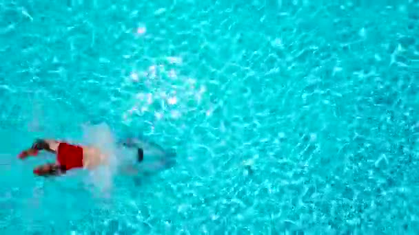 Вид сверху, как человек прыгает и ныряет в бассейн и плавает под водой — стоковое видео
