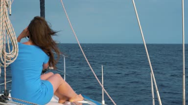 Yat ve ufuk dürbün ile keşfetmek aboard kadın mavi bir elbise oturur
