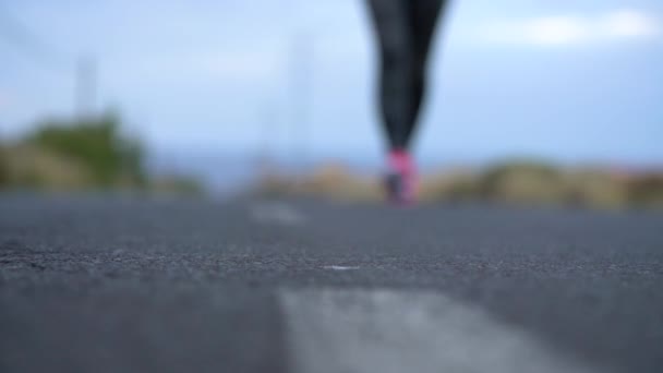 Zapatillas de correr - mujer atando cordones de zapatos en una carretera desierta en una zona montañosa. Movimiento lento — Vídeos de Stock