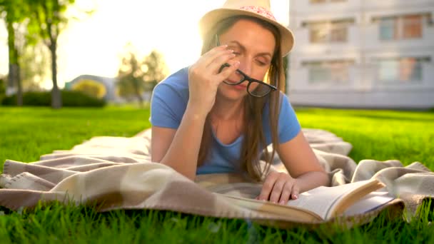 夕暮れ公園で毛布に横たわって本を読んでガラスの少女 — ストック動画