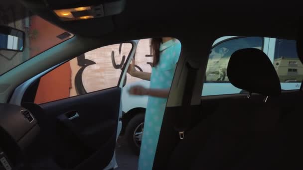 Mujer poner una chaqueta en el asiento del coche y se sienta en el asiento del conductor, con la intención de arrancar el motor — Vídeo de stock