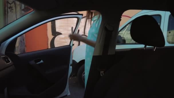 女性は車の座席にデニム ジャケットを置いて運転席に座り エンジンを起動しようとして — ストック動画