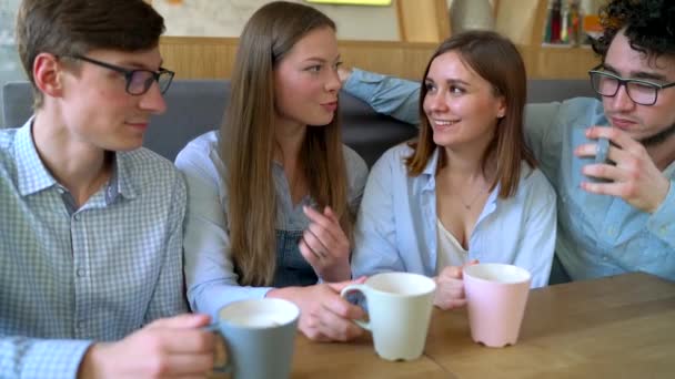 Jóvenes amigos se sientan en un café, toman café y se divierten comunicándose. Movimiento lento — Vídeo de stock
