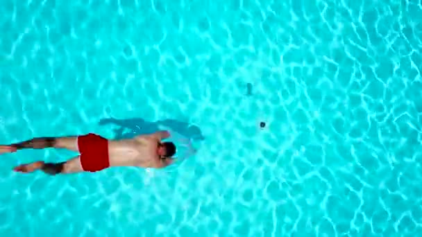 Vista desde arriba mientras un hombre salta y se sumerge en la piscina y nada bajo el agua — Vídeo de stock