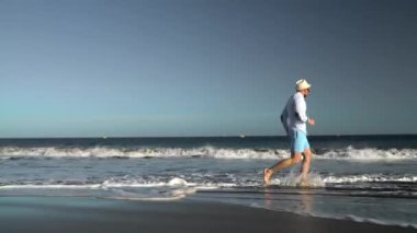 Mutlu adam, günbatımında okyanus plaj boyunca çalışır. Kaygısız modern yaşam kavramı. Tenerife, canarinha Adaları