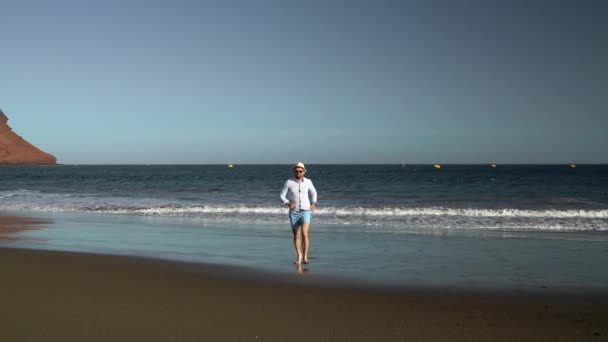 O homem feliz corre da praia do oceano ao pôr-do-sol. Conceito de vida moderna despreocupada. Tenerife, Ilhas Canárias. Movimento lento — Vídeo de Stock