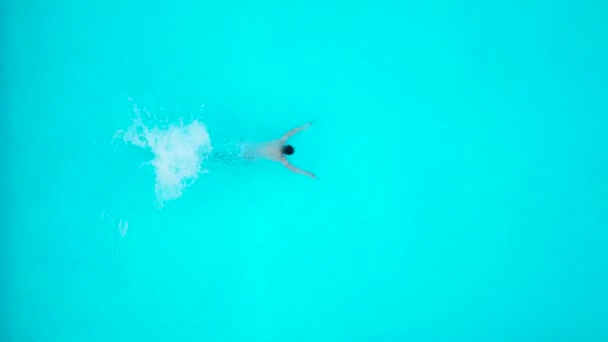 Uitzicht vanaf de top als een mens springen en duiken in het zwembad en de stekken onder water — Stockvideo