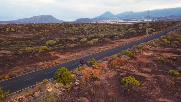 Vista aérea do ciclista viajando por uma estrada deserta — Vídeo de Stock