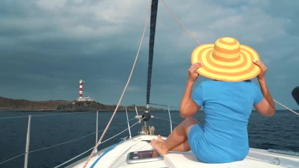 Frau mit gelbem Hut und blauem Kleid ruht an Bord einer Jacht zur Sommersaison auf hoher See — Stockvideo