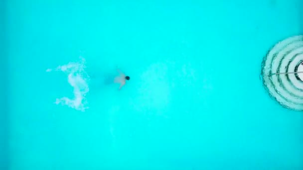 Blick von oben, wie ein Mann springt und in den Pool taucht und unter Wasser schwimmt — Stockvideo