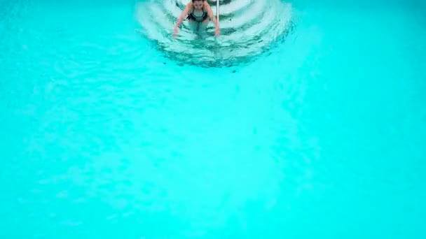 Blick von oben, als eine Frau im schwarzen Badeanzug im Pool schwimmt — Stockvideo