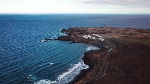 View from the height of rocky coastline with white buildings and a lighthouse on Tenerife, Canary Islands, Spain. Wild Coast of the Atlantic Ocean — Stock Video