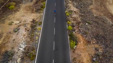 Kadının havadan görünümü görünümü Günbatımında geri ıssız asfalt yol boyunca çalışır. Arka planda dağlar