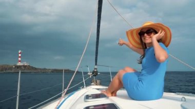 Kadın sarı hat ve mavi elbise kız gemiye lighthouse yakınındaki bir yat yaz sezonu ocean adlı aittir