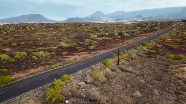 Вид сверху на автомобиль, едущий по пустынной дороге — стоковое видео