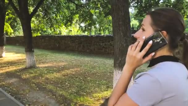 Женщина в разговоре на смартфоне и эмоционально жестикулирует во время прогулки по улице, закрыть — стоковое видео
