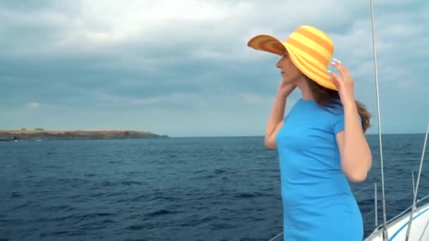 Donna in un cappello giallo e vestito blu ragazza riposa a bordo di uno yacht durante la stagione estiva al mare — Video Stock