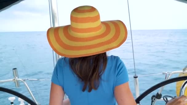 Женщина в жёлтой шляпе и синем платье, стоящая и улыбающаяся на яхте в летний сезон у океана — стоковое видео