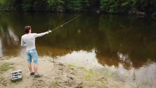 Pescador con caña de pescar en la orilla del río. El pescador atrapa un pez. Concepto de escapada rural — Vídeos de Stock