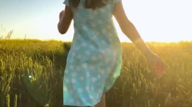 Sarı bir şapka yeşil buğday sahada koşan üzerinde gökyüzü günbatımı güzellik kız. Özgürlük kavramı. Günbatımı buğday alanında
