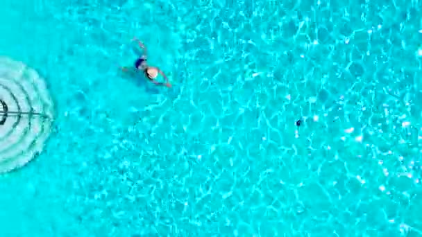 Blick von oben, als eine Frau im blauen Badeanzug im Pool schwimmt — Stockvideo