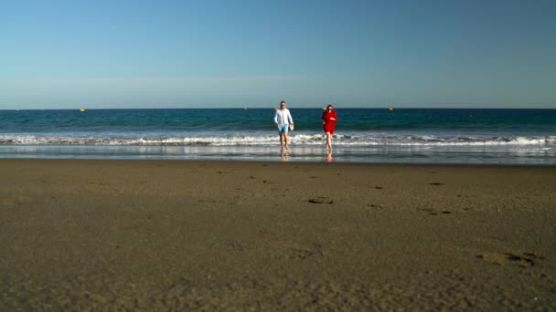 Couple amoureux sans soucis courir de l'eau sur la plage. Côte océanique pittoresque de Tenerife, îles Canaries, Espagne. Mouvement lent — Video