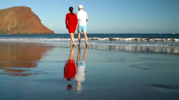 ビーチの上を歩く水に屈託のない愛のカップル。カナリアン諸島、スペイン テネリフェ島美しい海海岸 — ストック動画