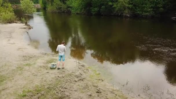 川の土手の漁師は釣り竿との空中写真。男の漁師は、魚をキャッチします。田舎での休暇の概念 — ストック動画
