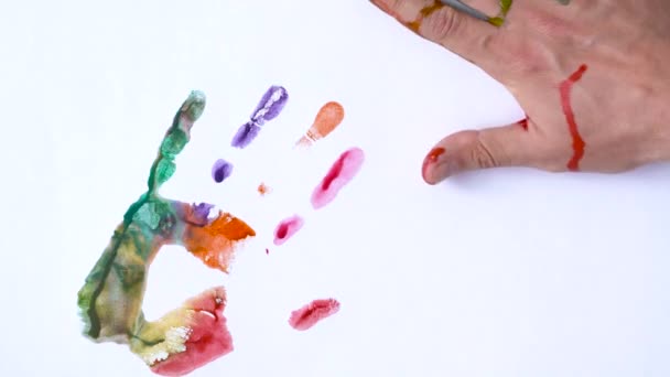 Conceito criativo - homem e mulher fazem impressões de suas mãos pintadas em um fundo branco — Vídeo de Stock