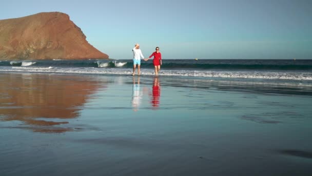 Paar verliefd zorgeloos het water lopen op het strand. Pittoreske Oceaan kust van Tenerife, Canarische eilanden, Spanje — Stockvideo