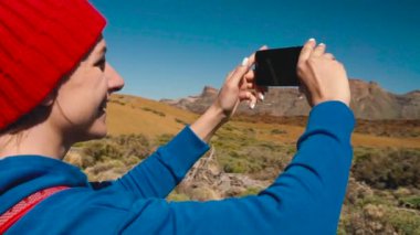 Teide Milli Parkı üzerinde hiking etkin uzun yürüyüşe çıkan kimse kadın ve fotoğraf manzara smartphone üzerinde yapar. Ağır çekim. Tenerife, Kanarya Adaları, İspanya sırt çantası olan beyaz kadın. Ağır çekim