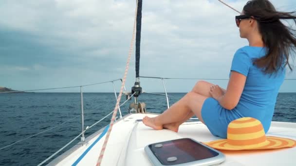 Woman in a yellow hat and blue dress girl rests aboard a yacht near the lighthouse on summer season at ocean. Slow motion — Stock Video