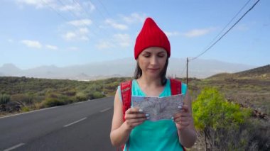 Güneşli bir yolda otostop ve yürüyüş gezgin kadın. Bir güneşli ülke yolda bir yolculuğa başlamak için bir gezintiye arayan backpacker kadın. Ağır çekim