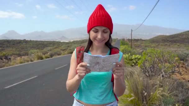 Viaggiatore donna autostop su una strada soleggiata e passeggiate. Backpacker donna in cerca di un passaggio per iniziare un viaggio su una strada di campagna illuminata dal sole — Video Stock