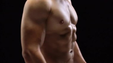 Adam bir kas güçlü vücut yakın çekim bir siyah arka plan üzerinde gösterir.