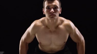 Adam bir halter alıştırmalar stüdyoda siyah bir zemin üzerine eğitim yapıyor