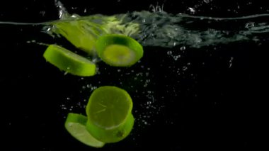 Kireç dilimleri düşmek ve float su, siyah arka plan, ağır çekim