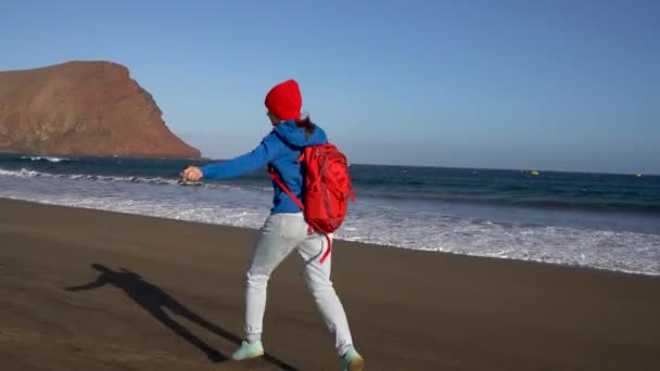 Donna escursionista attiva corre e salta sulla spiaggia. Giovane donna caucasica con zaino a Tenerife, Isole Canarie, Spagna — Video Stock