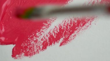 Parlak pembe akrilik boya ile beyaz kağıt üzerinde bir boya fırçası ile çizim yakın çekim