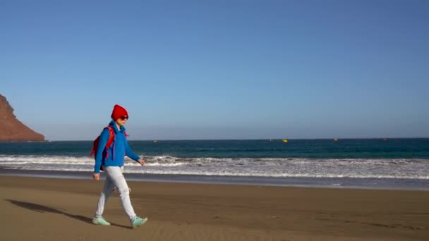 Etkin uzun yürüyüşe çıkan kimse kadın sahilde yürüyor. Tenerife, Kanarya Adaları, İspanya sırt çantası olan beyaz kadın — Stok video