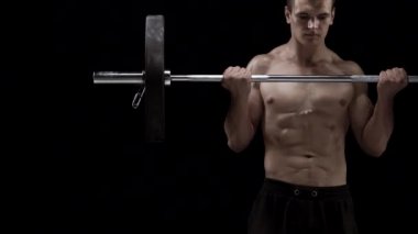 Adam bir halter alıştırmalar stüdyoda siyah bir zemin üzerine eğitim yapıyor