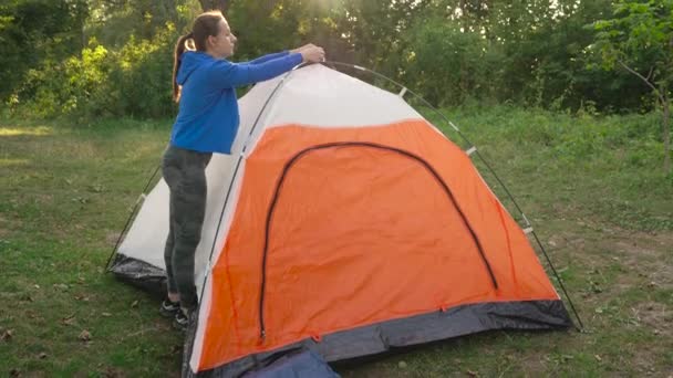 Vrouw zet een toeristische tent in het bos — Stockvideo