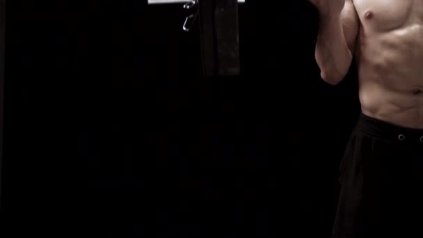 Man doet oefeningen met een barbell, training op een zwarte achtergrond in de studio. Halve lichaam in frame — Stockvideo