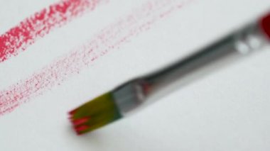 Parlak pembe akrilik boya ile beyaz kağıt üzerinde bir boya fırçası ile çizim yakın çekim
