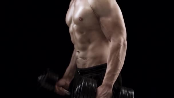 男子用哑铃弯曲双手 在演播室的黑色背景上训练他的二头肌 侧面观察 肌肉强健的身体 — 图库视频影像