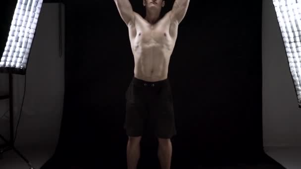 Man is doing exercises with a barbell, is engaged in a crossfit on a black background in the studio — Stock Video