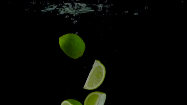 Pedaços de limão caem e flutuam na água, fundo preto — Vídeo de Stock